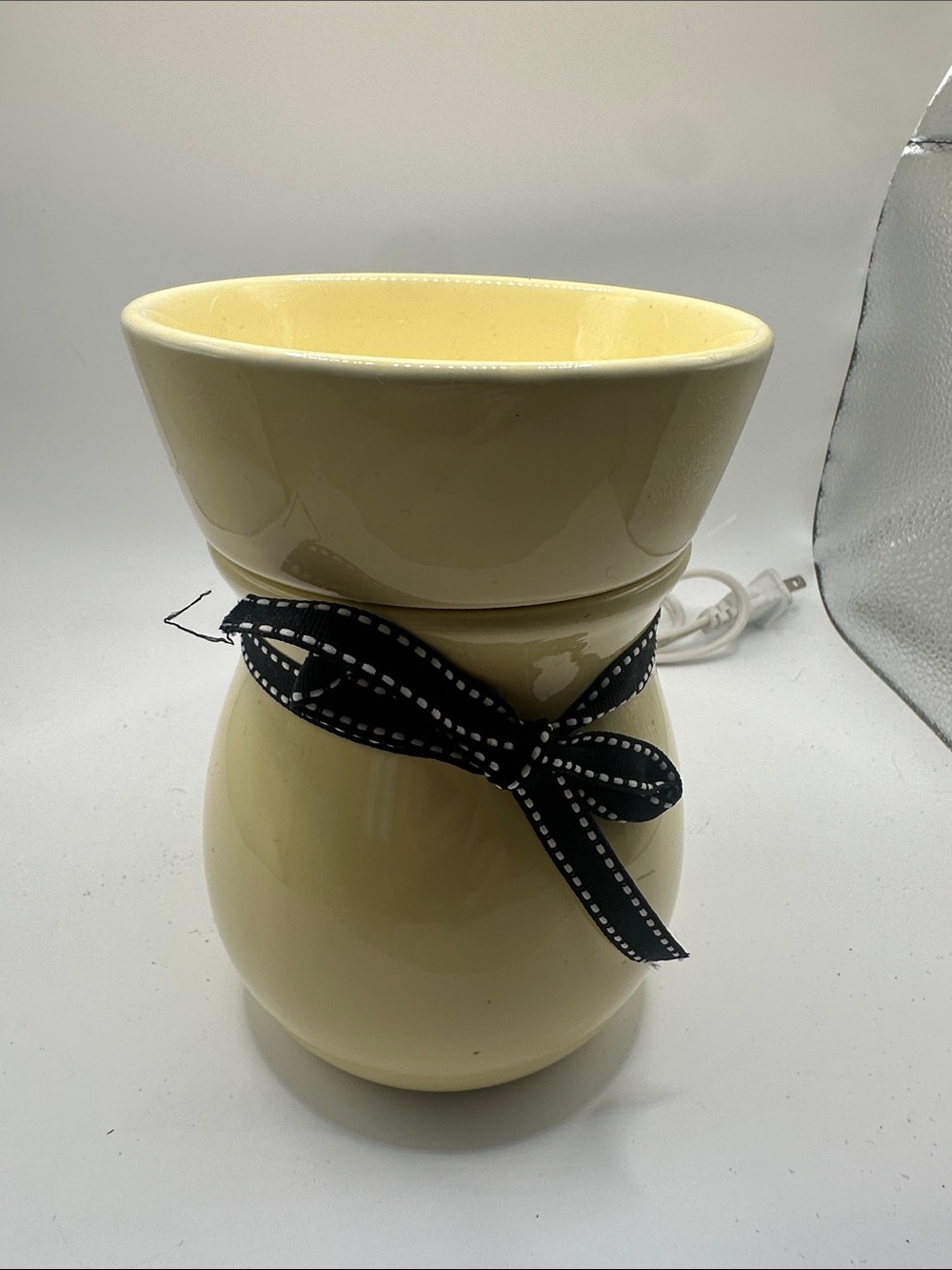 pale yellow ceramic wax warmer adorned with a black-and-white polka dot ribbon